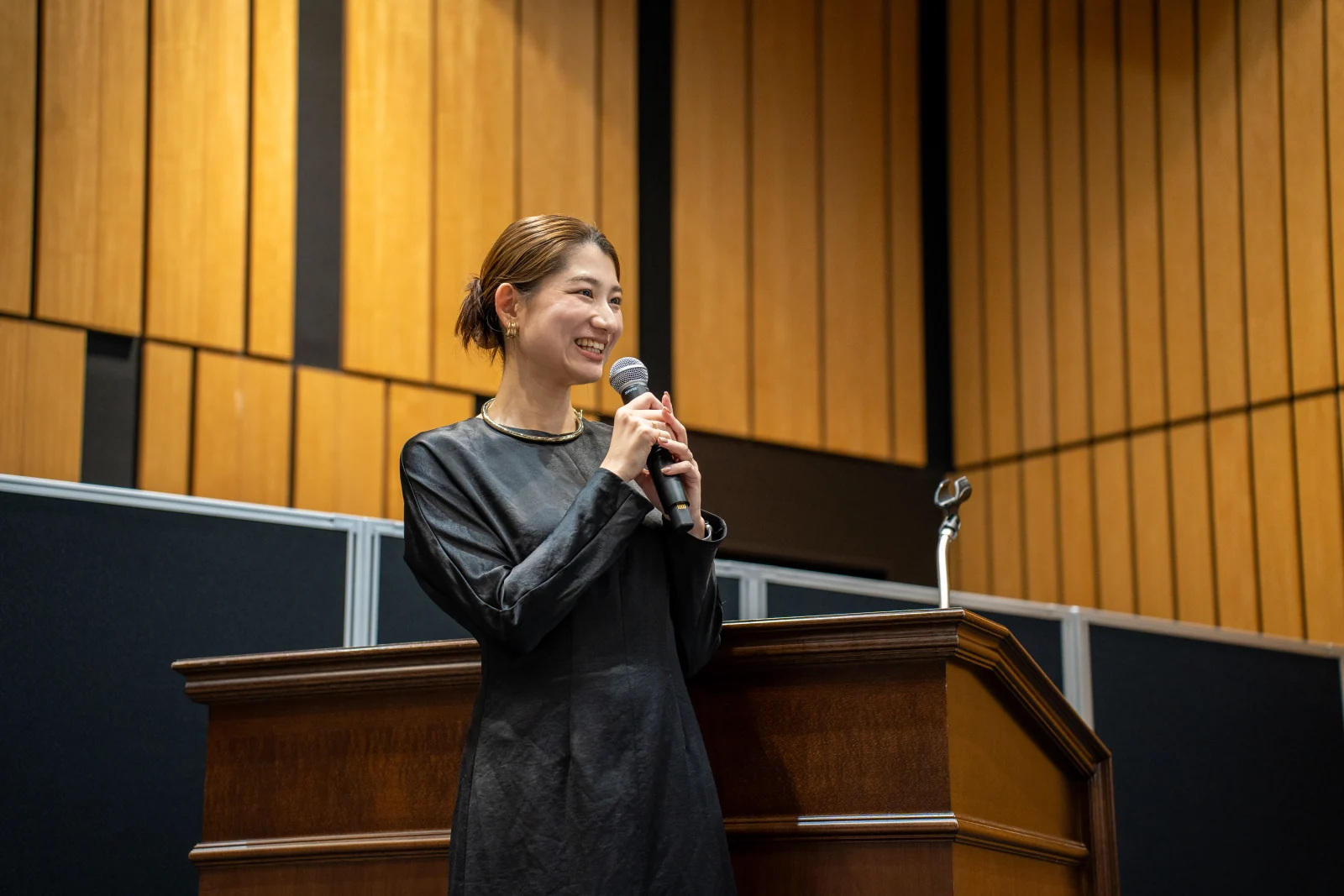 会場で笑顔でマイクを持つMCの岡田美咲さん